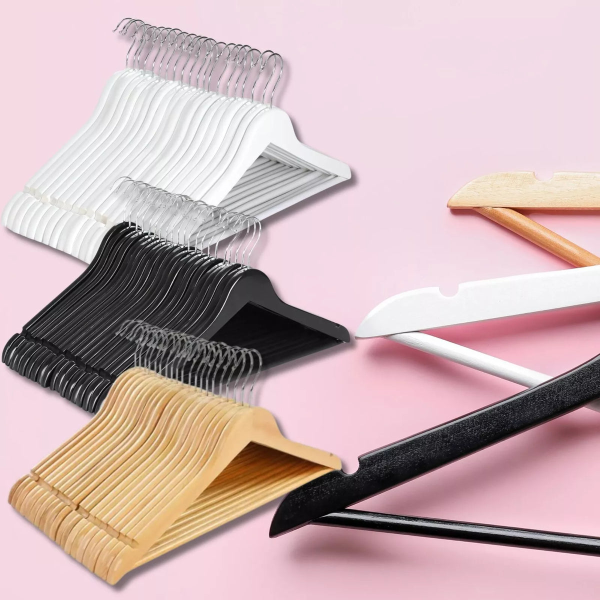 Set of hangers including wooden, black, white, and clear types on a pink background